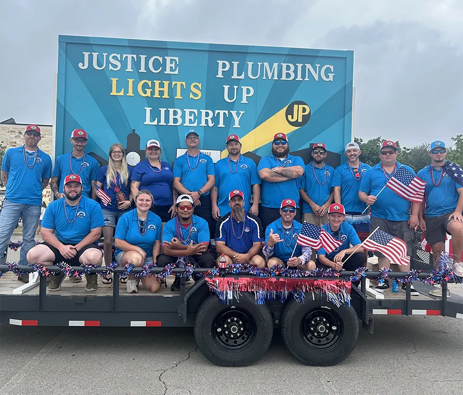 Team members on Justice Plumbing float in Granbury area parade, highlighting local plumbing repair, sewer cleaning, and community engagement.